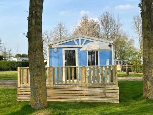 a blue tiny house in a field between two trees at Camping Le Romantic in Steenvoorde +15 photos