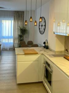a kitchen with white cabinets and a clock on the wall at Oasis de Paz Cullera in Cullera