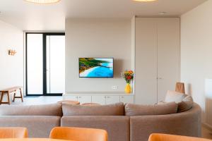 a living room with a couch and a tv on a wall at La Douce Douve in Heuvelland