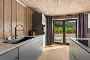 a kitchen with a sink and a large window at Det Kosekroken – Nordic Style Holiday Home by the Fjord in Vradal