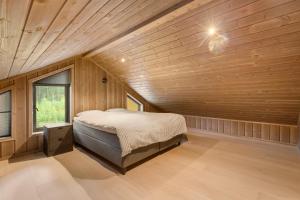 a bedroom with a bed in a room with wooden walls at Det Kosekroken – Nordic Style Holiday Home by the Fjord in Vradal