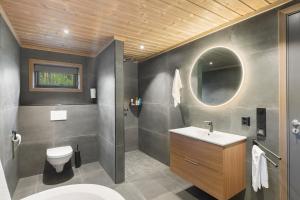 a bathroom with a toilet and a sink and a mirror at Det Kosekroken – Nordic Style Holiday Home by the Fjord in Vradal +25 photos