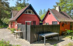 a red house with a wooden fence in front of it at Amazing Home In Aakirkeby With Wifi in Vester Sømarken