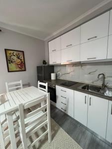 a kitchen with white cabinets and a table and a sink at Qetësia Borsh in Borsh