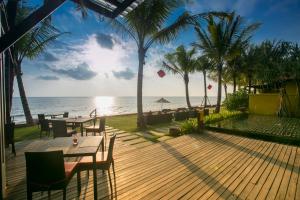 a wooden deck with tables and chairs on the beach at Chongfah Beach Resort Khaolak - SHA Extra Plus in Khao Lak