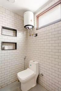 a white bathroom with a toilet and a window at Divine India Service Apartment,Studio,J-267 Saket in Jāmb +9 photos