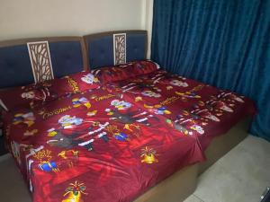 a bed with a red comforter with flowers on it at استيلا هايتس الساحل الشمالي in Dawwār ‘Abd al Qādir Qāsim