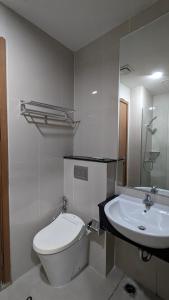 a white bathroom with a toilet and a sink at Vasaka The Reiz Condo in Medan