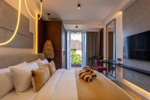 a hotel room with a bed with a teddy bear on it at Palermo Suites by Betterplace in Ubud