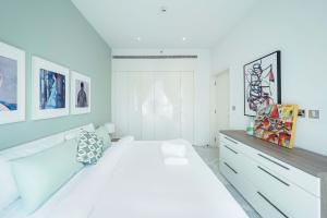 a white bedroom with a large bed and some pictures at Designer 1BR Retreat With Stunning Canal View in Dubai +5 photos