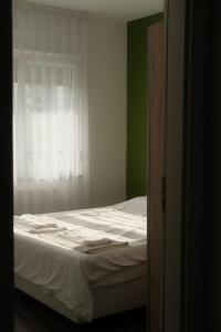 a bedroom with a bed and a window with white curtains at Green Apartment in Prishtina in Pristina
