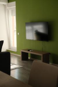 a living room with a flat screen tv on a green wall at Green Apartment in Prishtina in Pristina
