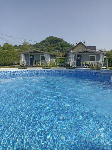 a swimming pool with blue water in front of a house at Domki u Ewci - Domki całoroczne in Uherce Mineralne
