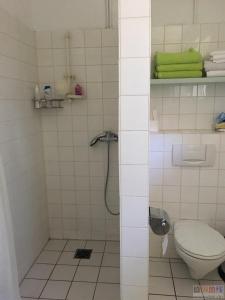 y baño de azulejos blancos con aseo y ducha. en New Living Nest, en Seevetal