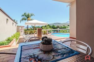 a table and chairs on a patio with a pool at Delizioso Appartamento in villa & Piscina Privata in Trabia