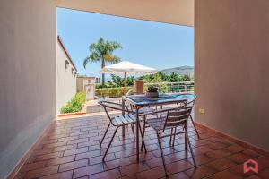 a patio with a table and chairs on a balcony at Delizioso Appartamento in villa & Piscina Privata in Trabia