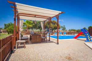 a pavilion with a table and a slide by a pool at Villa Santa Eulalia in Can Picafort