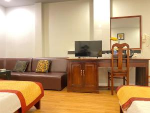 a living room with a couch and a desk with a television at DONA hotel in Can Tho