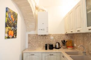 una cucina con mobili bianchi e un dipinto sul muro di Il Cuore del Borgo - Terrace In The Old Town a Locorotondo Altre 23 foto
