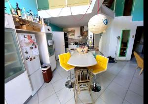 a kitchen with a table and yellow chairs at Villa avec jardin et piscine privés in Montpellier