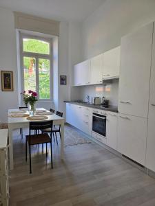 a kitchen with white cabinets and a table and a dining room at Palacinema Apartment - Locarno Old Town in Locarno