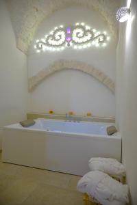 a white bathroom with a tub with a fancy ceiling at Relais I Quattro Cuori in Martina Franca