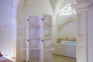 a white bathroom with a tub and a shelf at Relais I Quattro Cuori in Martina Franca
