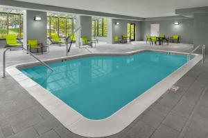 a pool in a hotel room with chairs and tables at SpringHill Suites Detroit Auburn Hills in Auburn Hills