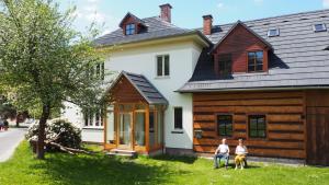 two people sitting in front of a house at Holiday House Malá Skála in Malá Skála