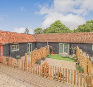 a house with a wooden fence in front of it at Gorgeous rural dog welcoming Milk Churn - Suffolk in Eye