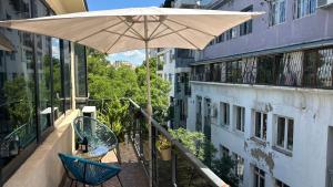 Una sombrilla y una silla en un balcón con un edificio. en Cloudy Tbilisi Apartment, en Tiflis