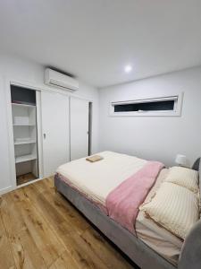a white bedroom with a bed and a window at Cozy room in Melbourne in Sunshine