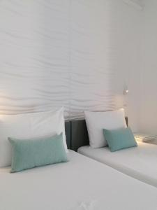 a white bed with two blue pillows on it at LITO STUDIOS APARTMENTS in Pythagoreio +10 photos