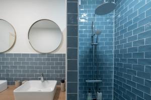 ein blau gefliestes Bad mit einem Waschbecken und einem Spiegel in der Unterkunft Gite La Goutte d'eau - Baby foot - 6 personnes LITS King & Queen size - Terrasse Vue étang in Saint-Josse + 35 Fotos