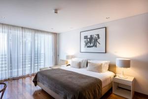 a bedroom with a large bed and a large window at Troia Design Hotel in Troia