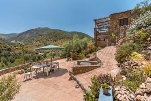 a patio with a table and an umbrella at Off-Grid - Puerto Mika in Órgiva