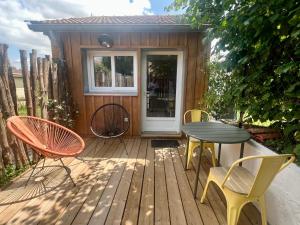 Una terraza de madera con sillas y una mesa y una puerta. en Casa Saint-Bris, en Villenave-dʼOrnon