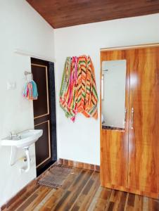 a bathroom with a wooden door and a sink at Hotel Krushnai Athvan Farm House in Khamshet