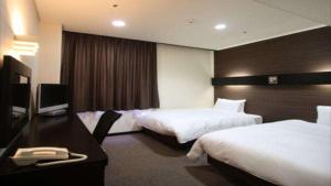 Una habitación de hotel con dos camas y un escritorio. en Green Rich Hotel Matsue Ekimae, en Matsue
