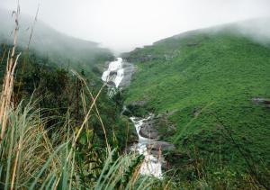 a mountain with a river on the side of a hill at Aruvi Mountain Villa Vagamon by VOYE HOMES in Vagamon
