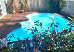 a blue swimming pool next to a wooden deck at Villa avec jardin et piscine privés in Montpellier
