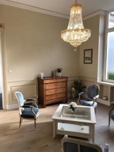 un soggiorno con sedie, tavolo e lampadario pendente di Maison d'hôte L'Esperance chic et calme a Saint-Omer