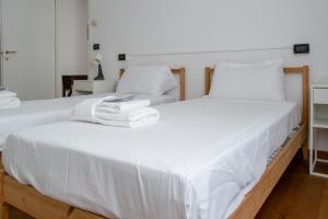 a bedroom with two beds with white sheets and towels at Welc-ōM Montegrotto Terrace View in Montegrotto Terme