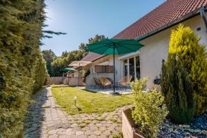 ein Haus mit einer Terrasse mit einem grünen Sonnenschirm in der Unterkunft Gite La Goutte d'eau - Baby foot - 6 personnes LITS King & Queen size - Terrasse Vue étang in Saint-Josse