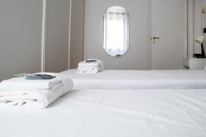 two white beds in a white room with a mirror at Welc-ōM Montegrotto Terrace View in Montegrotto Terme +21 photos