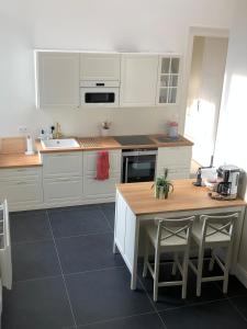 una cucina con mobili bianchi e un tavolo con sedie di Maison d'hôte L'Esperance chic et calme a Saint-Omer Altre 23 foto