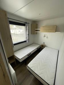 ein kleines Zimmer mit zwei Betten und einem Fenster in der Unterkunft Mobilhome in Saint-Jean-de-Monts + 26 Fotos
