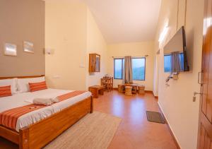 a bedroom with a bed and a flat screen tv at Aruvi Mountain Villa Vagamon by VOYE HOMES in Vagamon