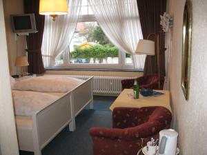 a bedroom with a bed and a chair and a window at Kurvilla Fürstin Pauline in Bad Salzuflen