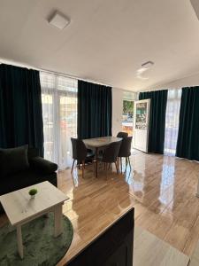 un soggiorno con tavolo, sedie e tende di Apartments Street a Struga Altre 5 foto
